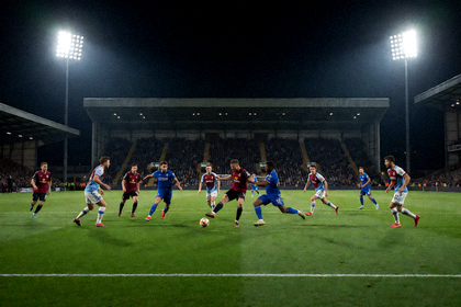 夜间球场灯光下两支球队进行联赛比赛的画面
